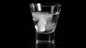 Image of an Aspirin tablet dissolving in a glass